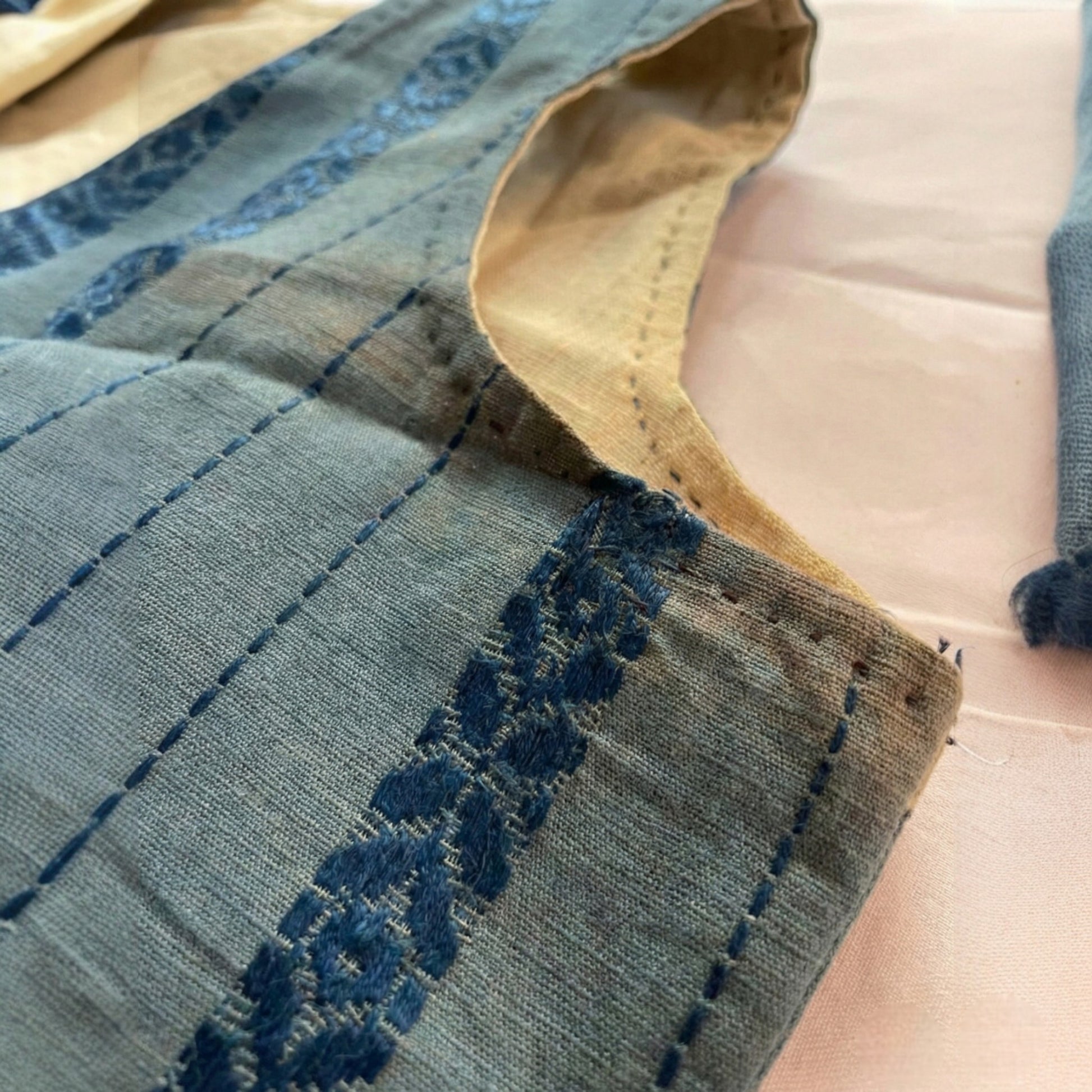 Close-up of a fabric with blue embroidery on a beige background Anatolian Heritage: Antique Ceremonial Vest (Cepken) from Denizli – Circa 1935-1945