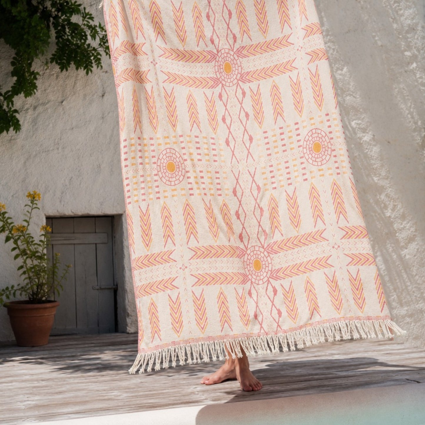 Person holding the Kilim Heritage reversible Turkish cotton muslin throw blanket outdoors, showcasing the ivory side with a jacquard woven kilim-inspired pattern.
