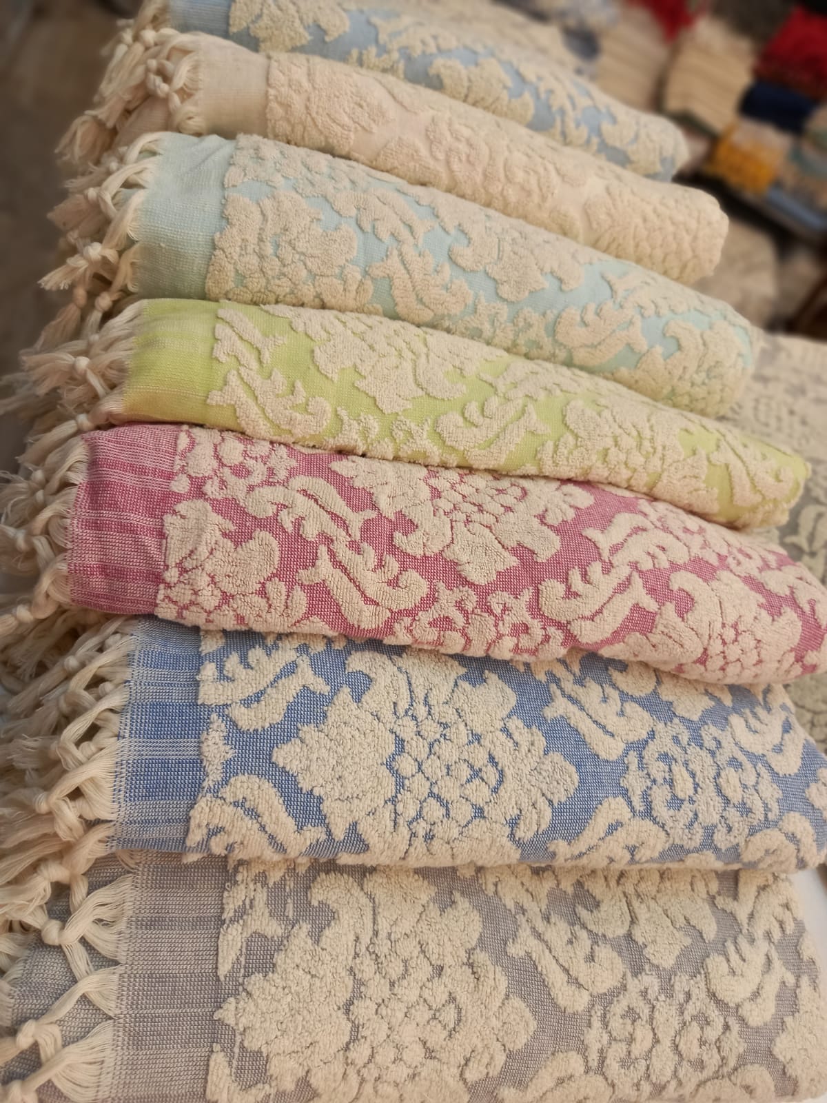 A selection of folded natural cotton Damascus Design Natural Cotton Turkish Terry Bath Towels in various colors, featuring a Damascus design pattern.